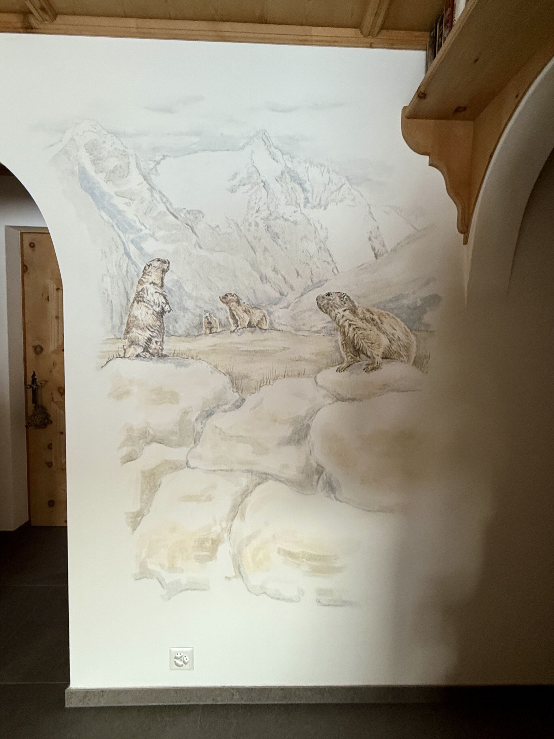 Detaillierte Wandmalerei zeigt Murmeltiere in alpiner Bergkulisse, kreative Raumgestaltung, Künstlerischer Wohnstil, Naturmotive.